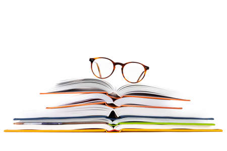 Stack of open book and reading glasses isolated on white backgroundの写真素材