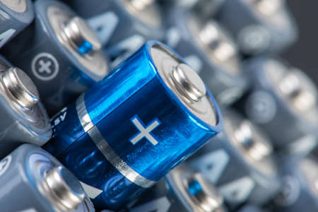 Stack of alkaline batteries size AA close up with focus on positive sign of one of themの写真素材