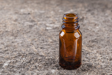 Small brown glass bottle for medicine, fragrance, essence oil and potion on natural stone backgroundの写真素材