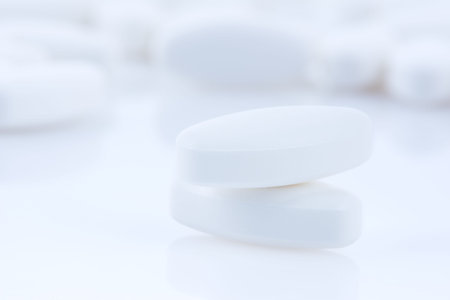 White pills on white background. Focus on foreground, soft bokeh.