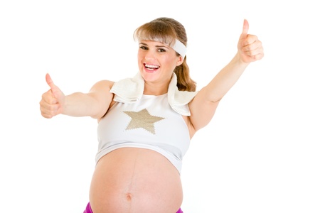 Smiling  pregnant woman in sportswear showing thumbs up gesture isolated on white 
の写真素材