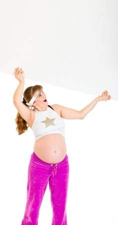 Surprised beautiful pregnant woman holding blank billboard over her head isolated on white
の写真素材