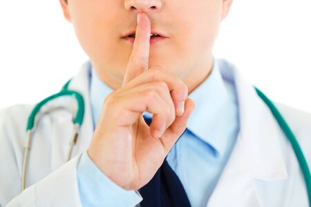 Medical doctor with finger at mouth isolated on white. Shh gesture
の写真素材