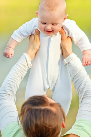 Mother holding laughing baby girl in hands outdoors at summer day. Close up.
の写真素材
