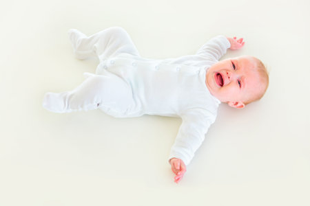 Crying four month old  baby girl laying on backの写真素材