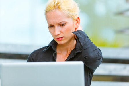 Concentrated modern business woman sitting on stairs at office building and using laptop