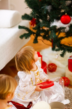 Two girls opening presents near Christmas treeの写真素材
