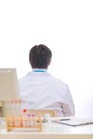 Medical doctor siting with his back to table at cabinetの写真素材