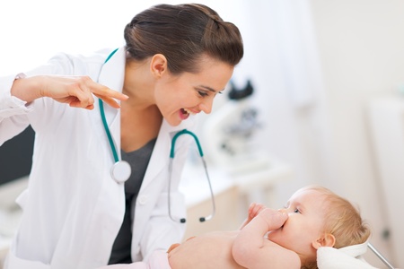 Pediatric doctor playing with baby on surveyの写真素材