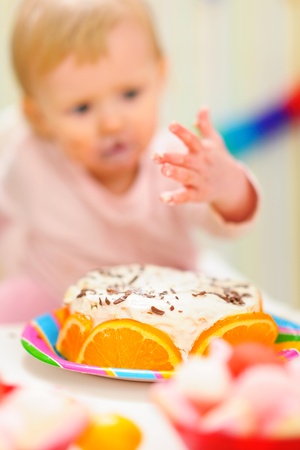 Closeup on birthday cake and eat smeared baby in background anonymousの写真素材