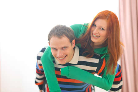 Smiling redhead girl piggybacking boyfriendの写真素材