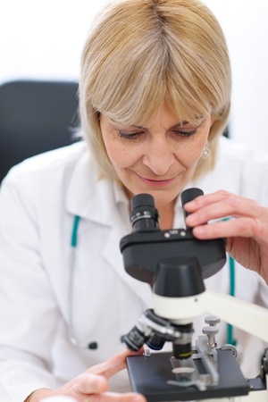 Senior female researcher looking in microscopeの写真素材