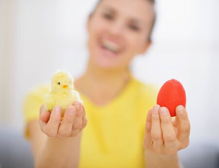 Woman holding red Easter egg and chickenの写真素材