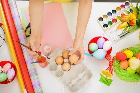 Preparations for Easter. Closeup on hands painting on egg.