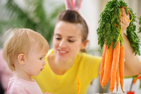 Mother showing baby bunch of carrotsの写真素材