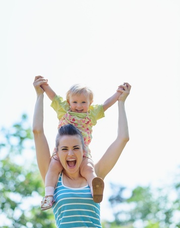 Happy mother with baby sitting on shouldersの写真素材