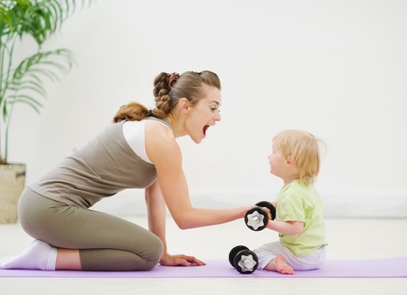 Baby helping mother lifting dumb-bellsの写真素材