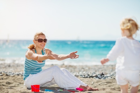 Mom playing with baby on beachの写真素材