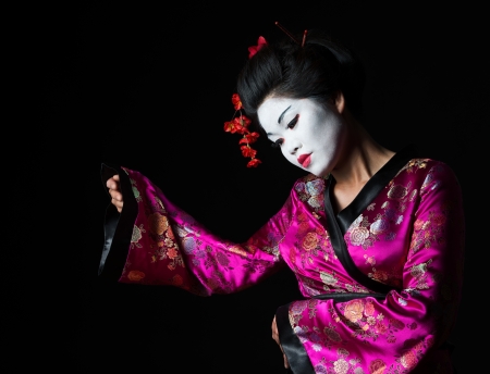 Portrait of geisha presenting something isolated on blackの写真素材