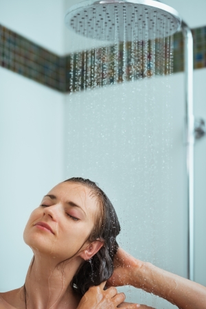 Relaxed woman taking shower under water jetの写真素材