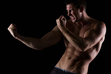 Angry muscular man in attack pose on blackの写真素材