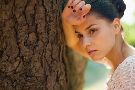 Thoughtful girl lean against treeの写真素材