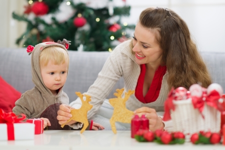 Mother showing baby Christmas deer shaped cookiesの写真素材