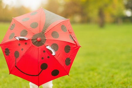 Baby hiding behind red umbrellaの写真素材