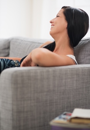 Smiling young woman laying on couchの写真素材