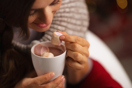 Closeup on woman taking out marshmallow from cup of hot chocolateの写真素材