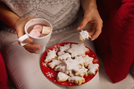 Closeup on woman eating Christmas cookie and drinking hot chocolate with marshmallowsの写真素材