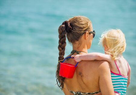Mother and baby looking on sea. Rear viewの写真素材