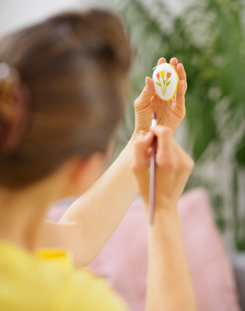 Woman drawing on Easter egg