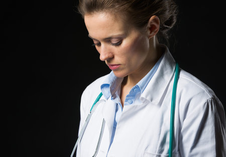 Portrait of thoughtful medical doctor woman isolated on blackの写真素材