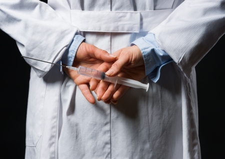 Closeup on medical doctor woman hiding syringe behind backの写真素材