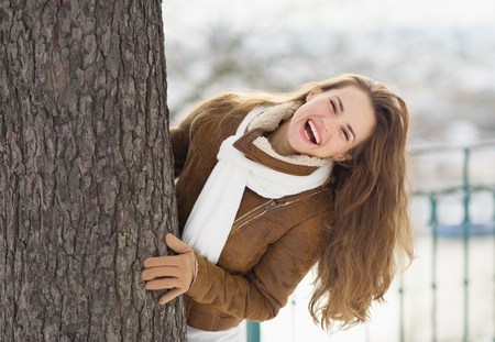 Happy young woman looking out from treeの写真素材