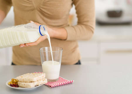 Closeup on young woman pouring milk into glassの写真素材