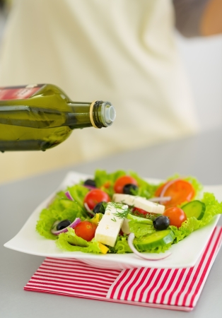 Closeup on woman adding olive oil into fresh saladの写真素材