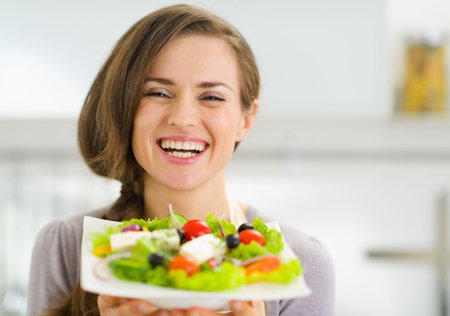 Smiling young woman showing fresh saladの写真素材