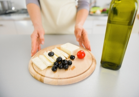 Closeup on young housewife giving olives and cheese on cutting boardの写真素材