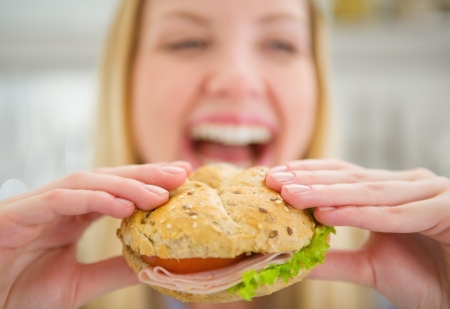 Closeup on burger in hand of smiling teenager girlの写真素材
