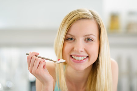 Smiling teenager girl with spoon of yogurtの写真素材