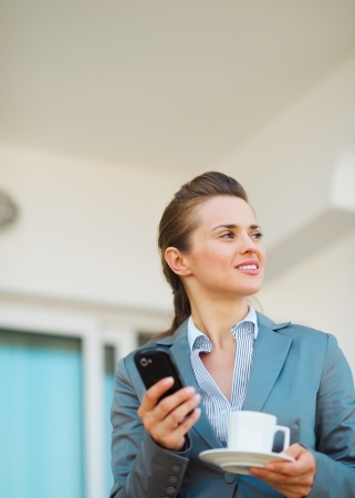 Thoughtful business woman with mobile phone on terraceの写真素材