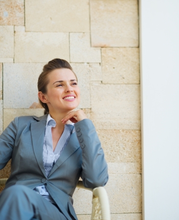 Happy business woman sitting on terrace with mobile phoneの写真素材