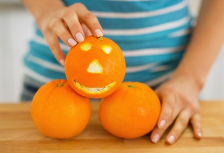 Closeup on orange with funny face in hand of young womanの写真素材