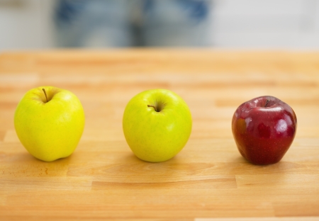 Two green and one red apple on cutting boardの写真素材