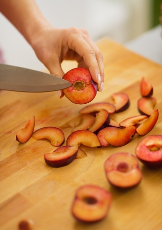 Closeup on young housewife cutting plumsの写真素材