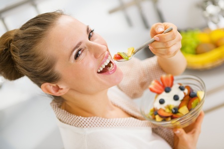 Happy young housewife eating fruits salad . rear view Happy young housewife eating fruits salad . rear view