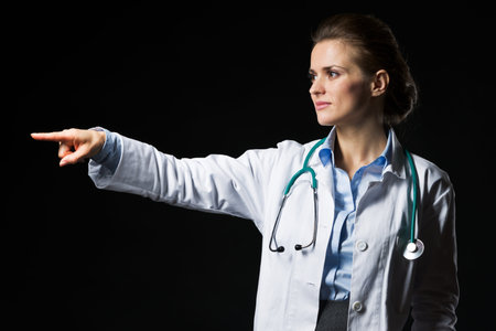 Doctor woman pointing on copy space isolated on blackの写真素材
