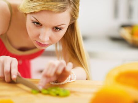 Young woman cutting salad in kitchenの写真素材